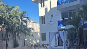 A hotel with a pool, outdoor seating, and palm trees. - Room-condo Facing the Pool in the Heart (Sosúa)
