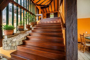 A wooden staircase with stone steps and potted plants, leading to a room with a dining table and chairs. - Bz81 Pé na areia na Praia da Ferradura (Buzios)