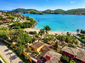 A coastal town with a beach, houses with terracotta roofs, and a clear blue sea. - Bz81 Pé na areia na Praia da Ferradura (Buzios)
