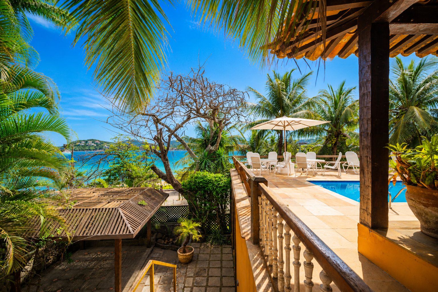 A poolside area with a view of the ocean, a wooden deck, and lounge chairs.