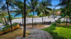 A paved pathway leading to a beach with palm trees and a clear view of the sea. - Bz81 Pé na areia na Praia da Ferradura (Buzios)