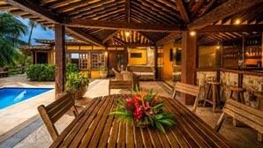 An outdoor covered patio with a pool, wooden furniture, and a bar area. - Bz81 Pé na areia na Praia da Ferradura (Buzios)