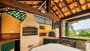 Un área de cocina al aire libre con horno de ladrillo, una parrilla y una mesa.
