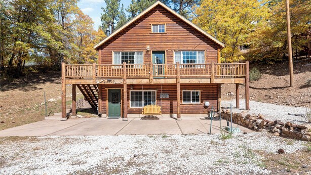 Een houten chalet met twee verdiepingen, een balkon, een veranda en een trap naar de ingang.