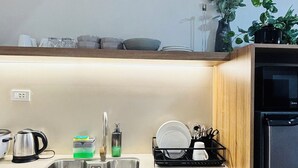 Eine moderne Küche mit Spüle aus Edelstahl, Holzschränken und einem schwarzen Kühlschrank.