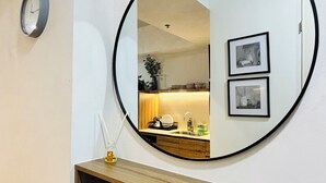 Ein Spiegel mit einer Holzkonsolen unterhalb, eine Uhr an der Wand und zwei gerahmte Bilder.