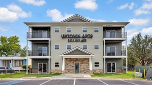 Ein mehrstöckiges Wohnhaus namens Uptown Apts in der Ivy Avenue 3111, mit einem zentralen Eingang, Balkonen und einem Parkplatz davor.