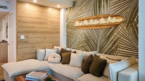 A modern living room with a sectional sofa, a wooden accent wall, and a decorative sign. - City Skyline View Private Studio at Roney Palace (Miami Beach)