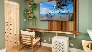 A living room with a TV mounted on a wooden wall, a wooden bench, a chair, and several potted plants. - City Skyline View Private Studio at Roney Palace (Miami Beach)