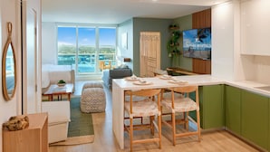 A modern kitchen with a dining area, wooden chairs, and a view of Miami Beach. - City Skyline View Private Studio at Roney Palace (Miami Beach)