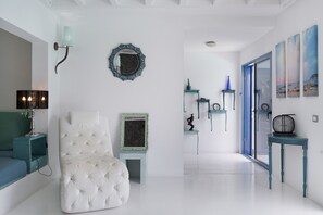 A modern interior with a white tufted chair, teal furniture, a mirror, and artwork on the walls. - Vacation Villa 'Lunamoon' with Private Pool, Wi-Fi and Air Conditioning (Unknown)