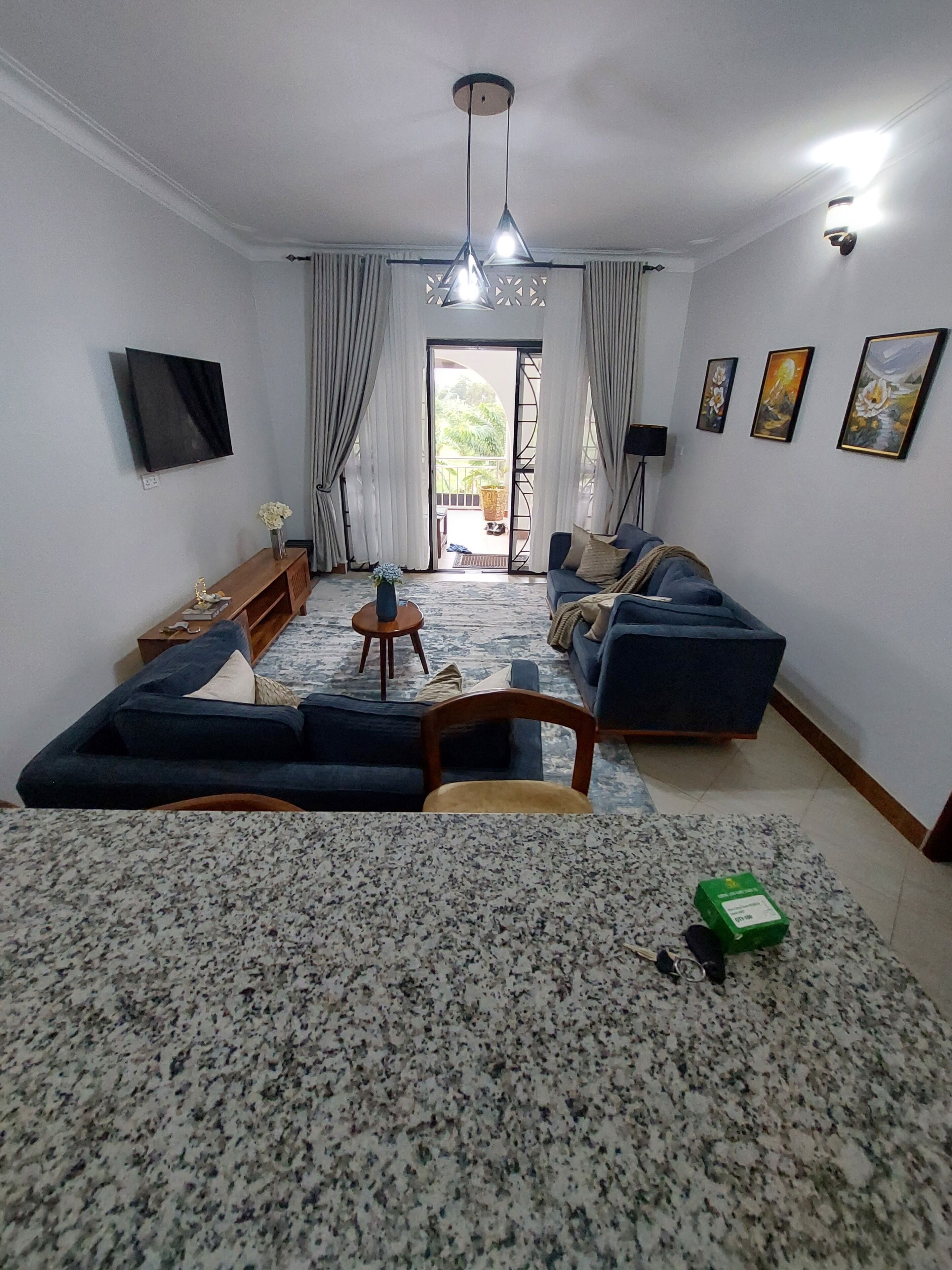 A living room with a sofa set, a coffee table, and a TV mounted on the wall.
