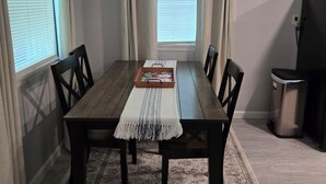 A dining area with a wooden table, chairs, a ceiling fan, and a rug. - Midwest City 2 Bed 2 Bath-Cottage on 15th, Cottage on 15th-Charming  2 Bedroom (Midwest City)
