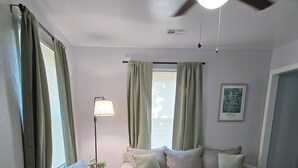 A living room with a sofa, a coffee table, a floor lamp, and a ceiling fan. - Midwest City 2 Bed 2 Bath-Cottage on 15th, Cottage on 15th-Charming  2 Bedroom (Midwest City)