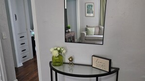 A hallway with a console table, a mirror, and a framed sign. - Midwest City 2 Bed 2 Bath-Cottage on 15th, Cottage on 15th-Charming  2 Bedroom (Midwest City)