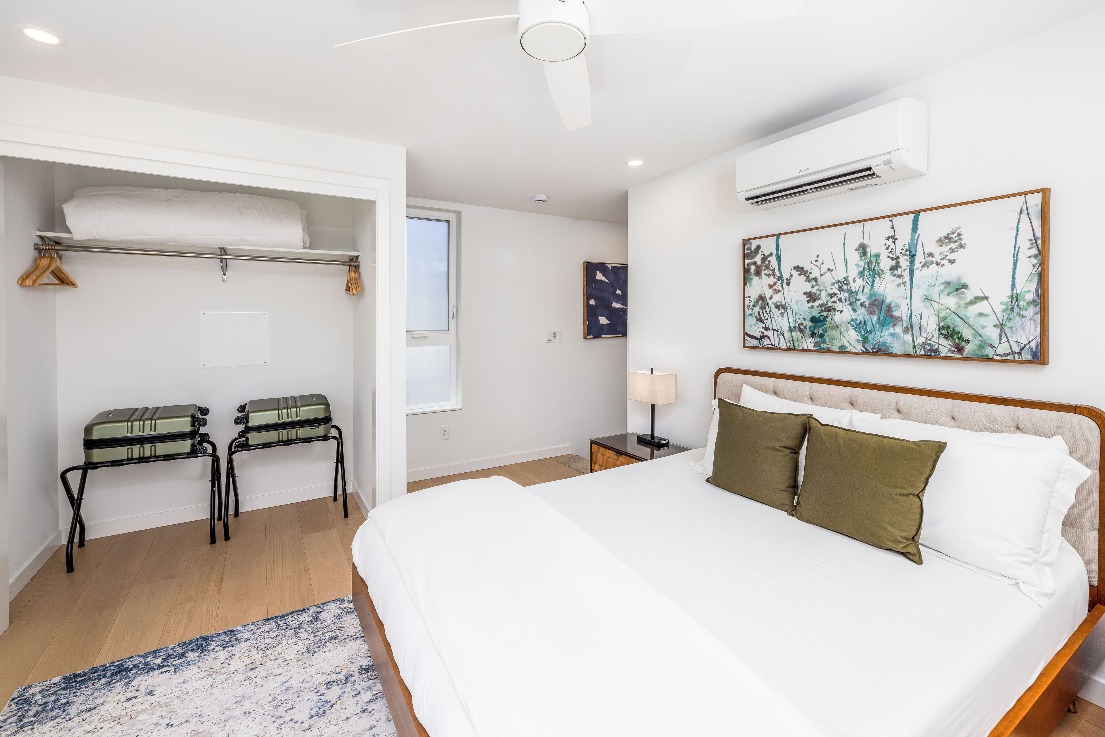 Een slaapkamer met een groot bed, een kledingkast, een nachtkastje en een airconditioner.