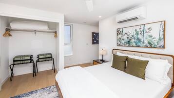 Een slaapkamer met een groot bed, een kledingkast, een nachtkastje en een airconditioner.