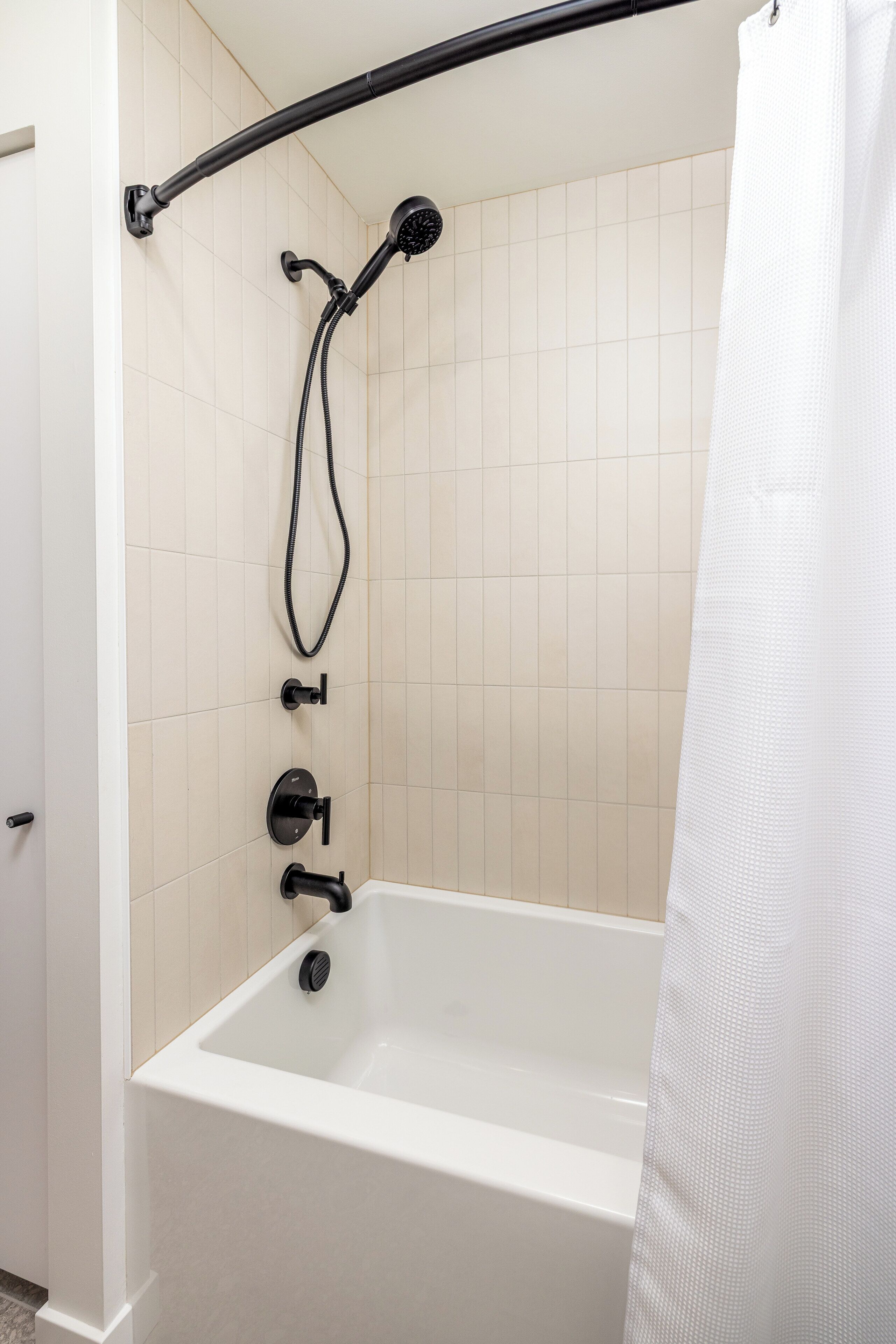 A bathroom with a bathtub, a shower head, and a curtain.