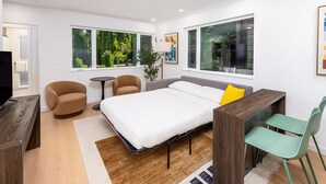 Un dormitorio moderno con una cama, dos sillones, una mesita y un escritorio.