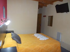 Un dormitorio con cama, lámpara de noche, espejo y puerta.
