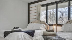 A hotel room with two beds, a large window with curtains, and a view of trees outside. - 7BR Monroe Getaway: Pool, Hot Tub, & Huge Living Space (Monroe)