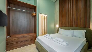 A hotel room with a large bed, a wooden wardrobe, and a flat-screen TV.