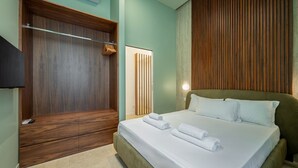 A hotel room with a large bed, a wooden wardrobe, and a flat-screen TV.