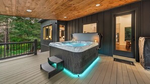 A hot tub on a wooden deck with a view of the surrounding area.