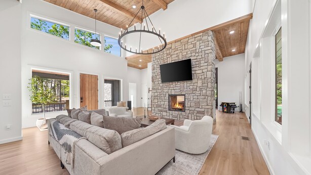 A spacious living room with a stone fireplace, a large sofa, and a flat-screen TV mounted on the wall.