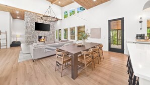 A spacious living area with a stone fireplace, a large dining table, and a cozy seating arrangement.