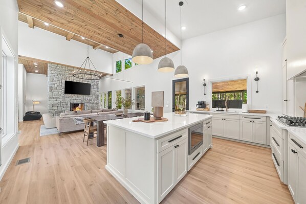 A modern kitchen with white cabinetry, a central island, and a stone accent wall.