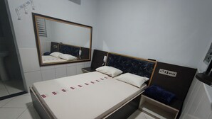 A hotel room with a bed, a bedside table, a mirror, and a control panel on the wall. - Hotel Flert Santana (Sao Paulo)