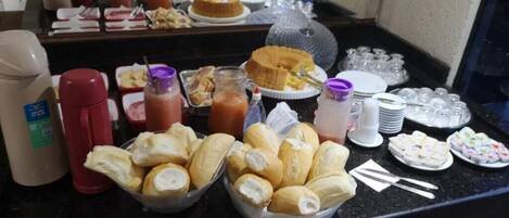 Un bufé con diversas opciones de comida, como pan, postres y bebidas.