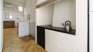 A modern kitchen with a black countertop, white cabinets, and a kettle. - Elegant Apartment in the Heart of Florence (Firenze)