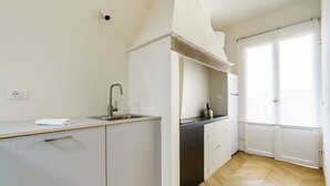 A modern kitchen with white cabinetry, a stainless steel sink, and a black countertop. - Elegant Apartment in the Heart of Florence (Firenze)