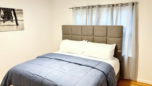 A bedroom with a bed, a ceiling fan, and a window with curtains. - Cozy 2-bedroom apartment with WiFi, AC, large outdoor balcony (Belleville)