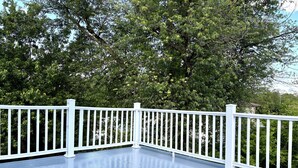 A blue deck with white railings and a tree in the background. - Cozy 2-bedroom apartment with WiFi, AC, large outdoor balcony (Belleville)