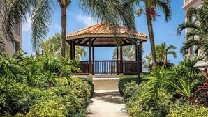 A covered outdoor area with a tiled roof, surrounded by lush greenery and palm trees. - Hidden Haven III - Cozy Studio (The Bight Settlement)