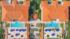 An aerial view of a resort with multiple swimming pools, sun loungers, and palm trees. - Hidden Haven III - Cozy Studio (The Bight Settlement)