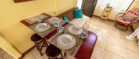 Una mesa de comedor dispuesta con platos, tazones y una taza, rodeada de sillas.