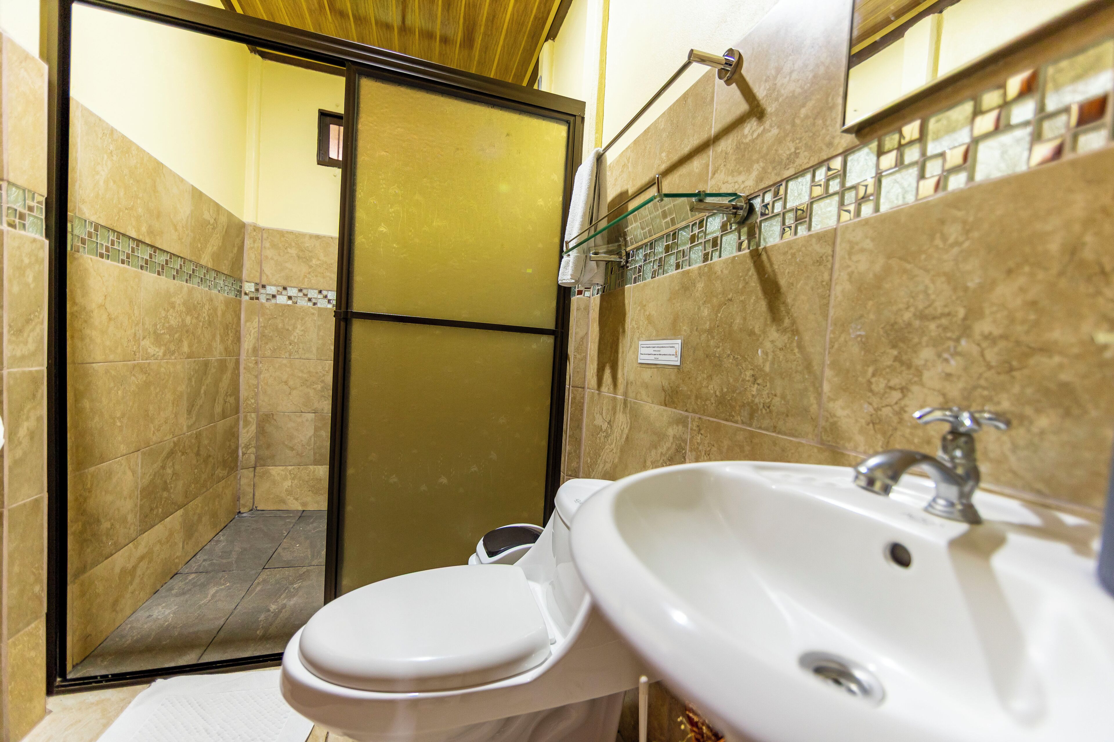 A bathroom with a toilet, sink, and shower area.