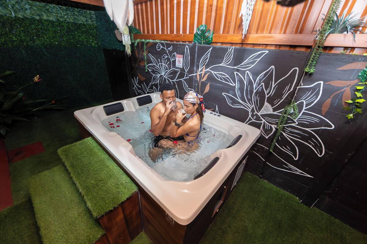 Ein Whirlpool mit floralem Wandbild, umgeben von künstlichem Gras.