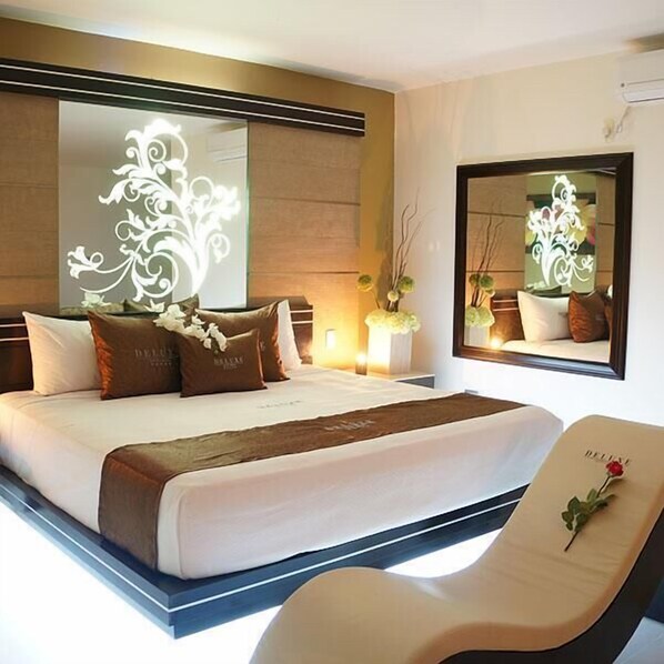 A modern hotel room with a large bed, a bedside table, a mirror, and a decorative wall panel. - Auto Hotel Deluxe (Emiliano Zapata)