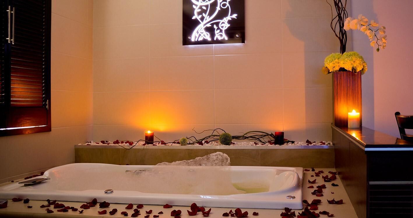 Un cuarto de spa con bañera, velas y un adorno en la pared.