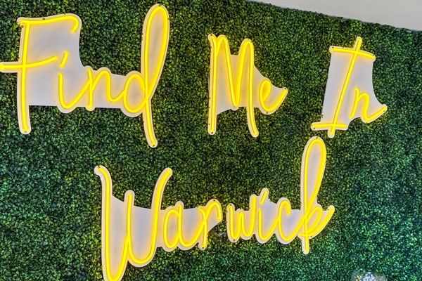 Instagrammable Touch: Bright neon sign invites fun in a lush green backdrop!