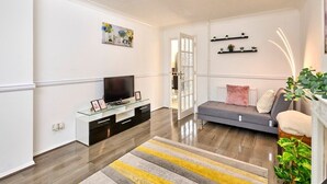 A modern living room with a flat-screen TV, glass coffee table, and a sofa. - Home in Milton Keynes (Great Holm)