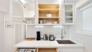 A modern kitchen with white cabinetry, a built-in oven, a coffee maker, a toaster, and a sink.
