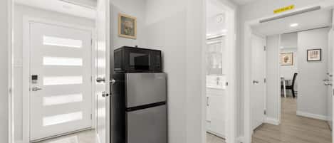 A modern kitchen with a black refrigerator, white cabinetry, and a microwave on top.