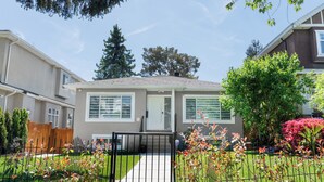 A residential house with a front yard, a wooden fence, and a metal gate.