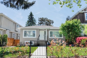 A residential house with a front yard, a wooden fence, and a metal gate.